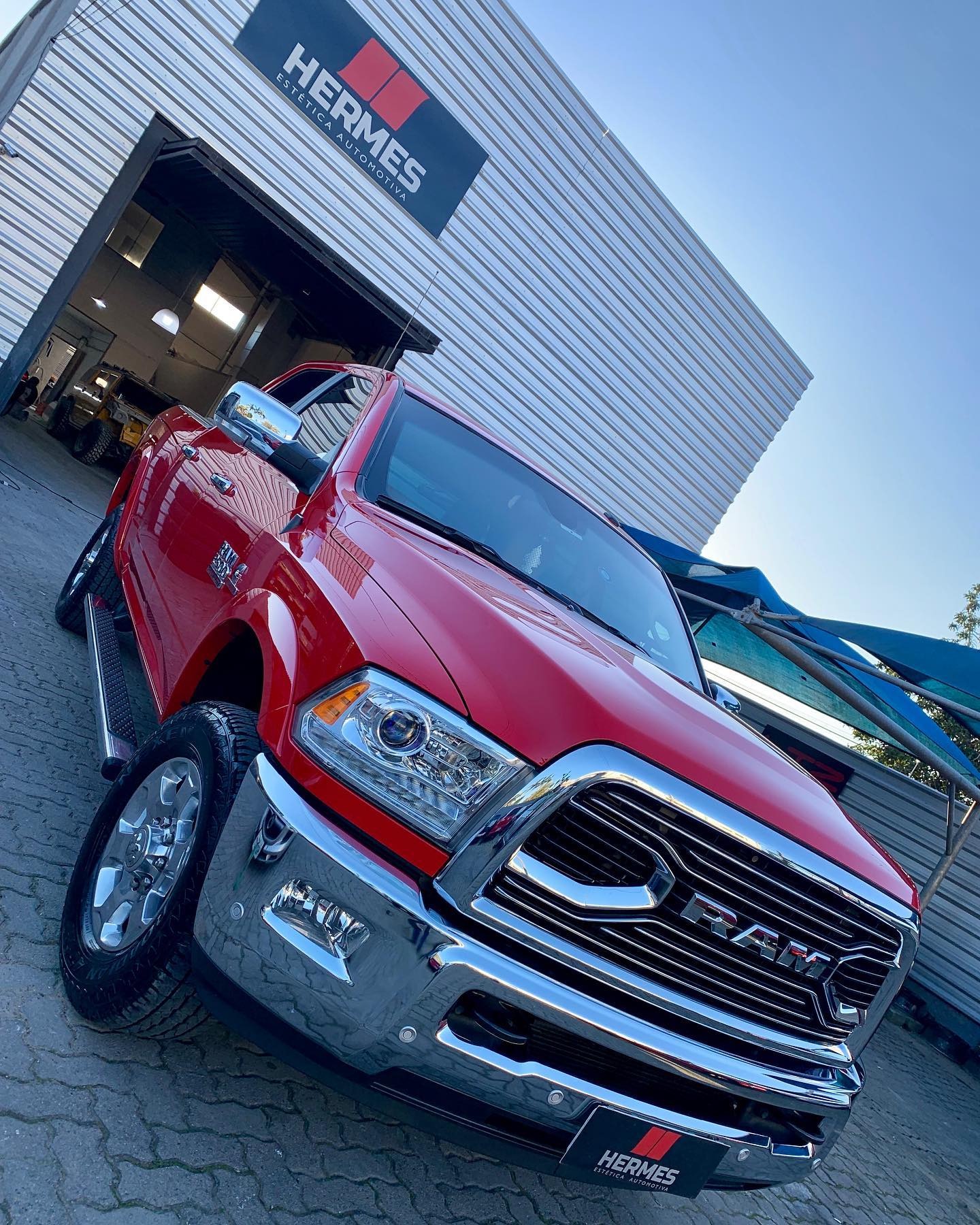 RAM 2500 vermelha customizada em frente à fachada da Hermes Estética Automotiva