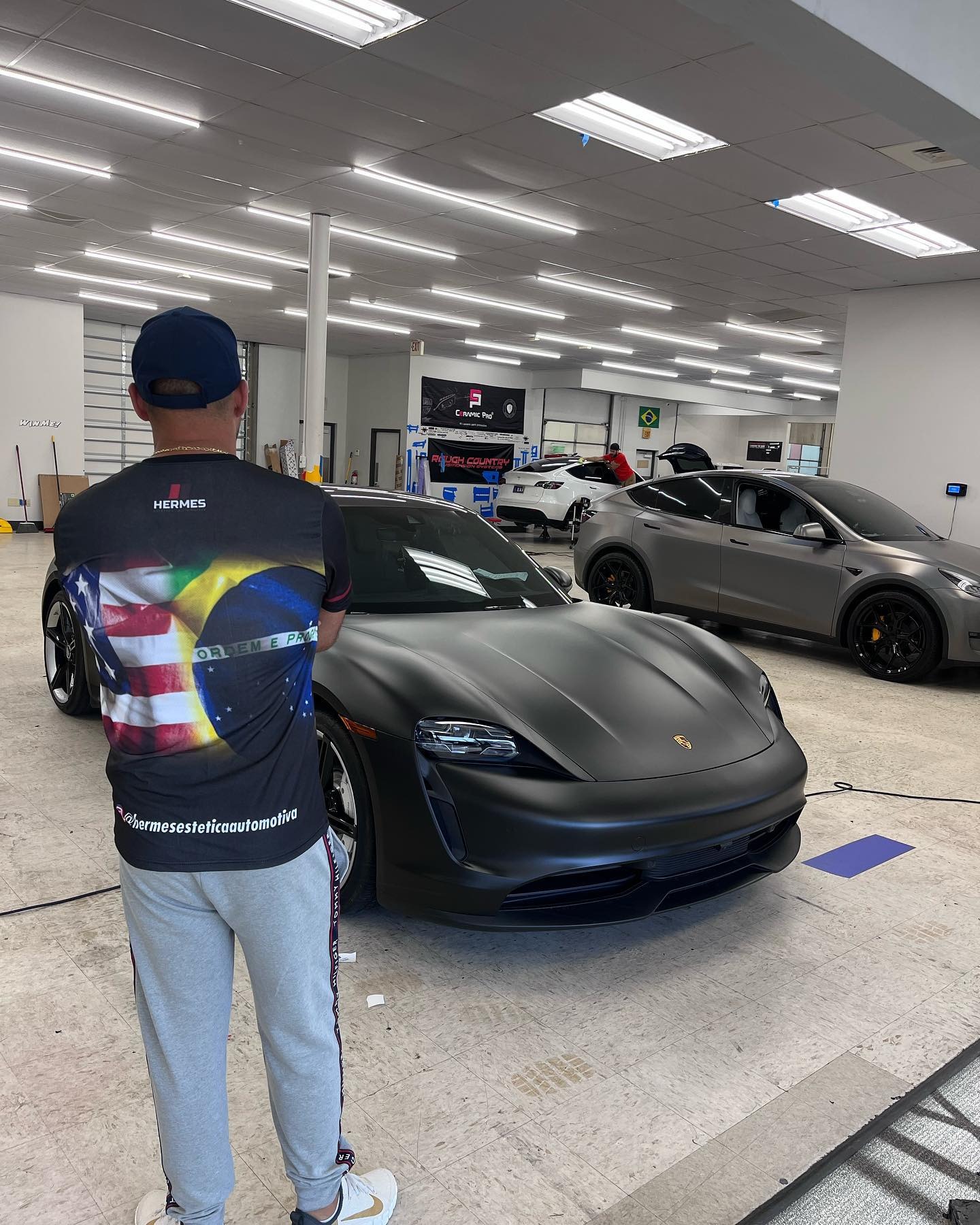 Porsche Taycan com envelopamento preto fosco no box da Hermes